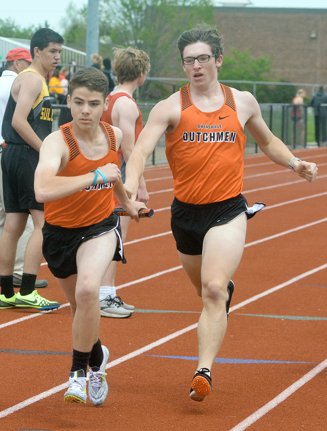 Hunter Lang (far left) reaches back for the baton from Noah Holtmeyer during the JV boys 4x800-meter relay in which the Dutchmen placed second behind Union.